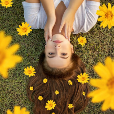 Mergina gulinti pievoje tarp gėlių